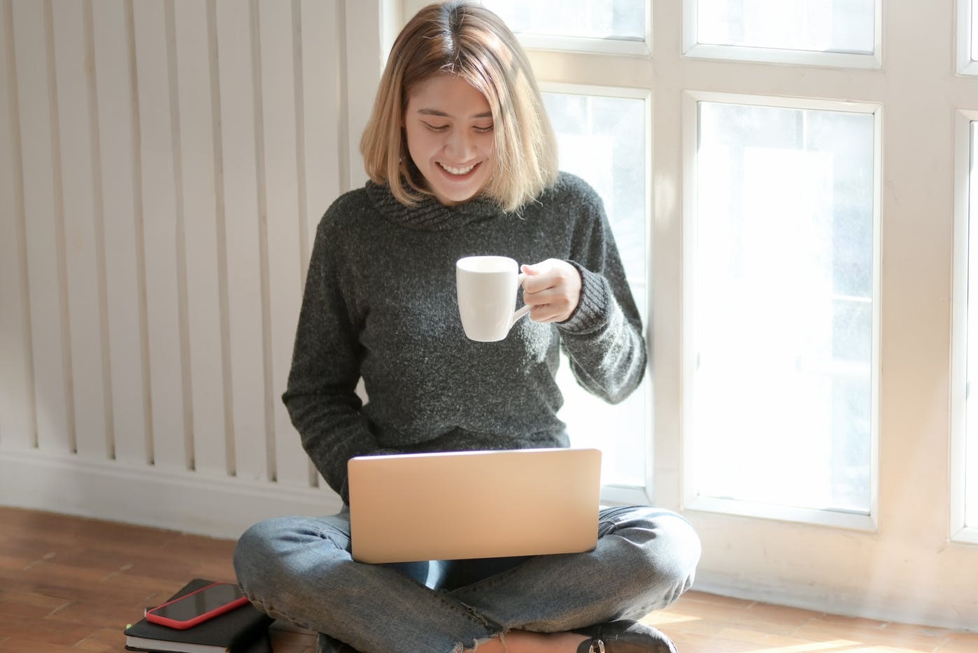 mujer sentada piso computadora taza de cafe