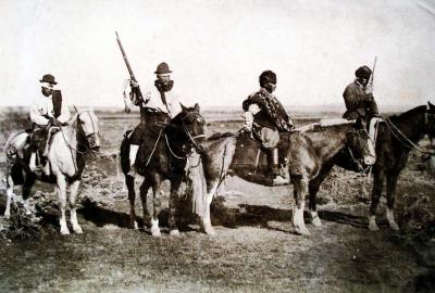 La imagen muestra una foto antigua de La Pampa en el siglo XIX, con jinetes a caballo