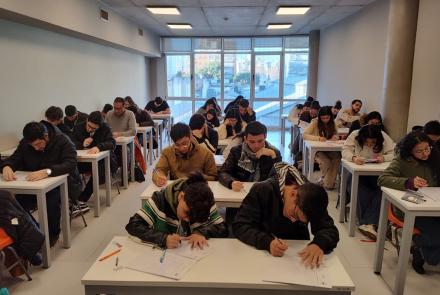 La imagen muetra una foto de estudiantes en un aula rindiendo el CEA en julio de 2024