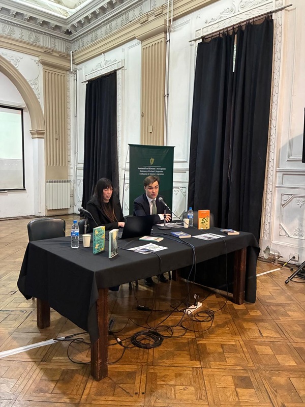 La imagen muestra la mesa de los oradores en el evento. En este caso la profesora Karina Guardia y el cónsul de Irlanda