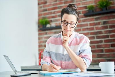 La imagen muestra a una joven mujer frente escribiendo sobre un cuaderno