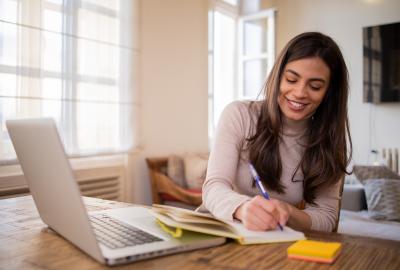 La imagen muestra a una mujer estudiando frente a una computadora