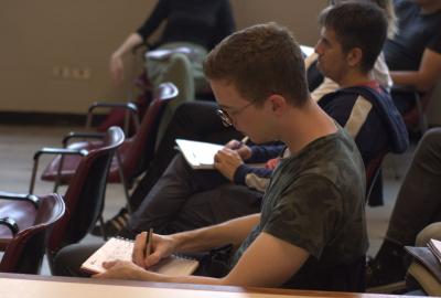 La imagen muesra a un estudiante exranjero en un aula, escribiendo