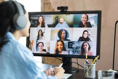 La imagen muestra a una mujer mirando al monitor de su computadora. está en una reunión (un meet) y en la pantalla aparecen otras personas