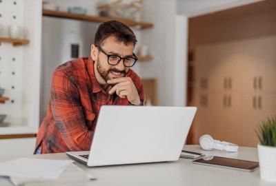 La imagen muesra a un hombre frente a una computadora