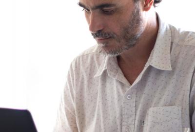 La imagen muestra a un hombre frente a una computadora