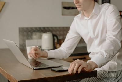 La imagen muestra a un hombre frente a una computadora, concentrado