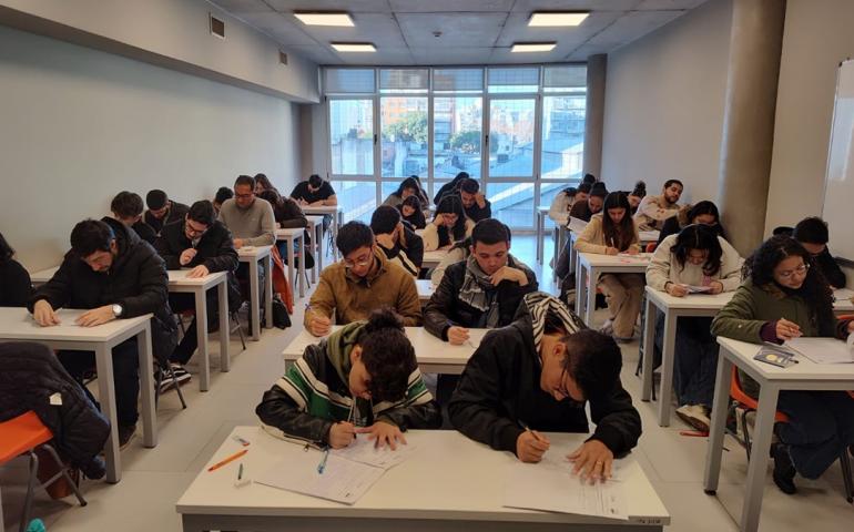 La imagen muetra una foto de estudiantes en un aula rindiendo el CEA en julio de 2024